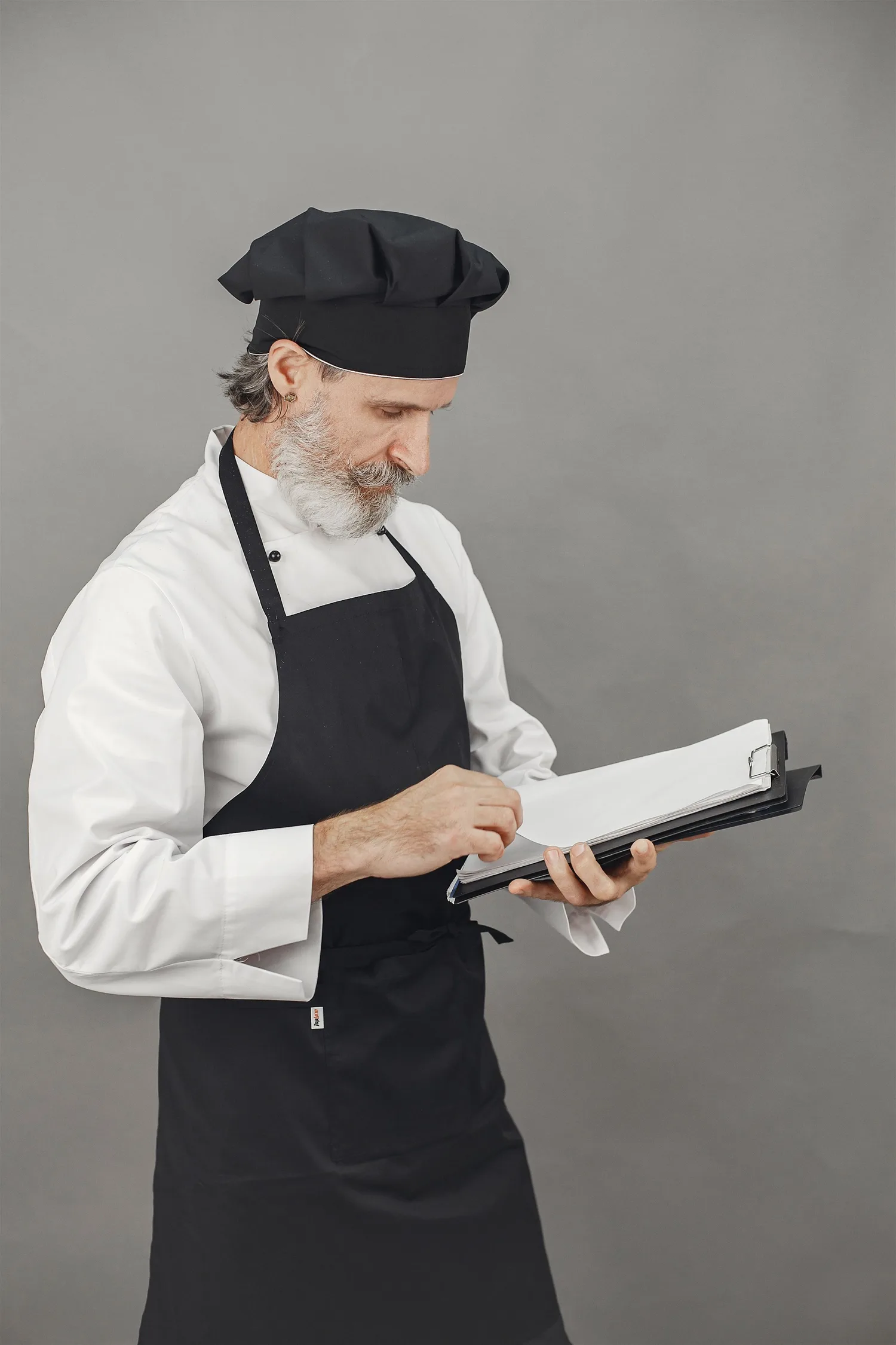 A chef in an apron checking notes on a clipboard