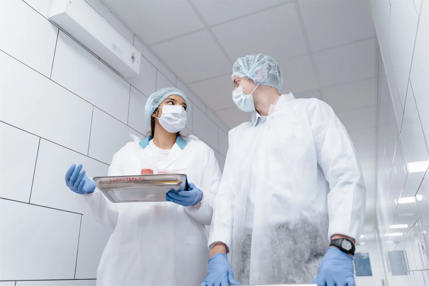 Two people in protective clothing reviewing a clipboard in a food preparation area